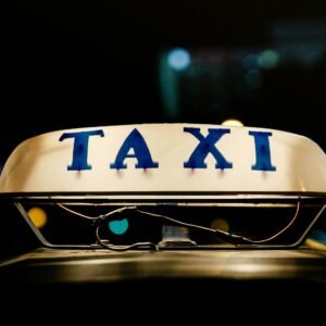 Close-up view of an illuminated taxi sign in a bustling city at night.